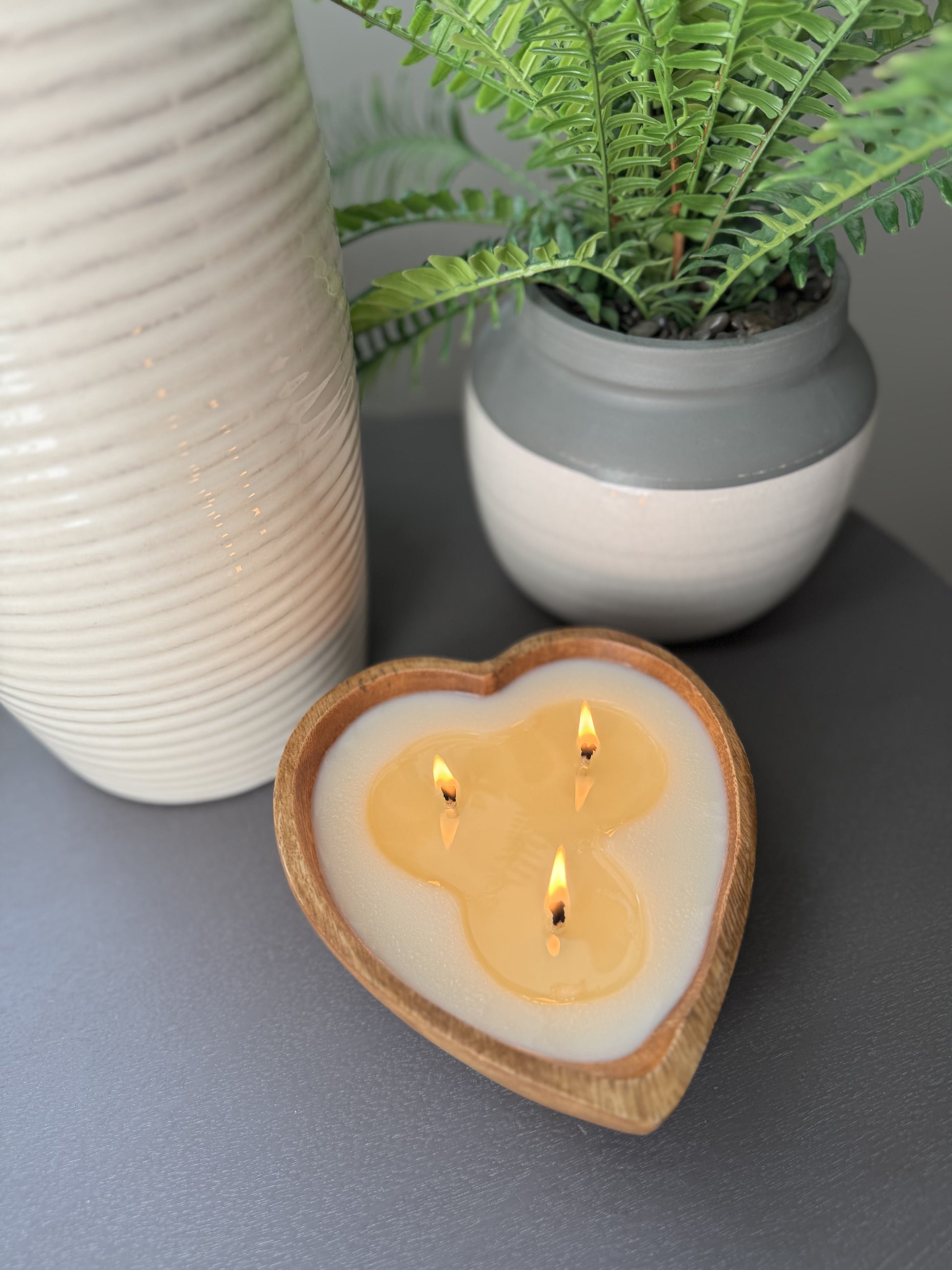 Top View of Lit wood bowl luxury scented candle on side table.